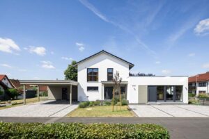 Einfamilienhaus als Holzrahmenbau mit Satteldach und Putzfassade und großem Carport